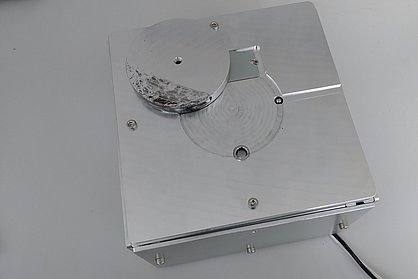 Helle Metallbox mit kleinen Öffnungen für Sensorik, Metallabdeckung und einem Kabel.