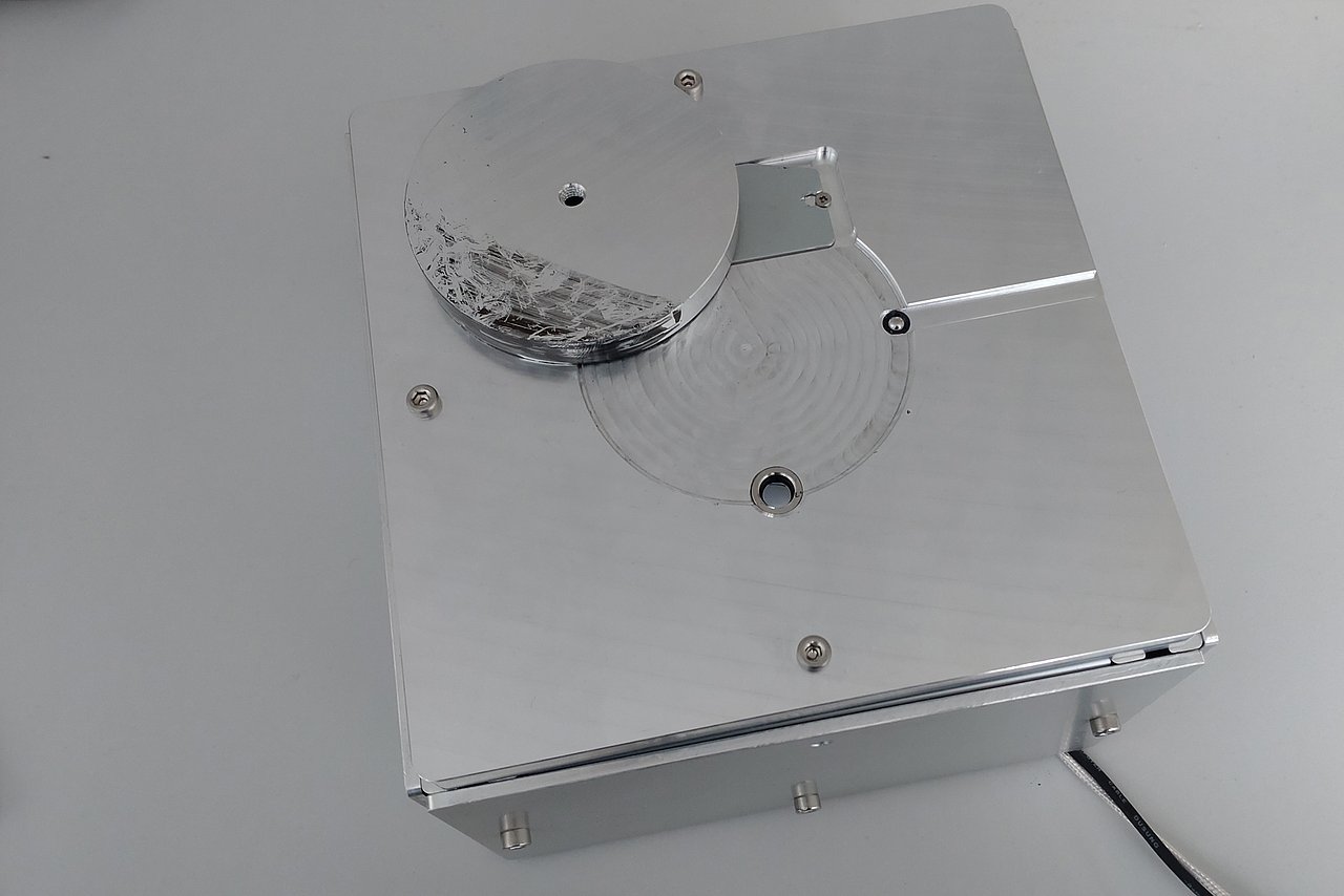 Helle Metallbox mit kleinen Öffnungen für Sensorik, Metallabdeckung und einem Kabel.