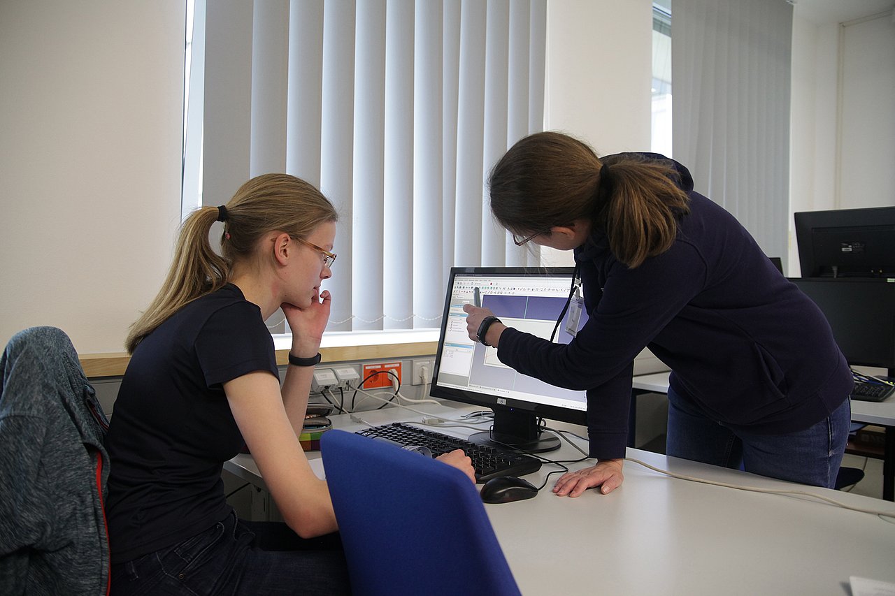 Einblick in die Konstruktion für z.B. 3D-Druck zum Forschungstag am IMMS. Foto: IMMS. Eine Schülerin vor einem PC-Monitor wird von einer Mitarbeiterin des IMMS beim Bedienen des Konstruktionsprogramms unterstützt.