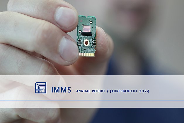 Hand with a small circuit board (about one finger wide and two high), on it the unencapsulated chip on which the structures can be seen.