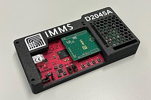 Kunststoff-Box mit Platinen und darauf verbautem Chip und IMMS-Logo sowie Chipnummer.   