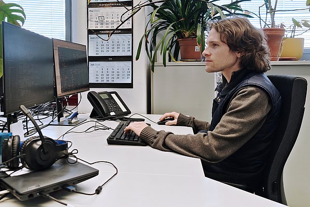 Arbeiten für die Implementierung der strukturierten, automatisierten Methodik Expert Design Plan (EDP) zur automatisierten Schaltungsauslegung, Simulation und Optimierung. Foto: IMMS. Ein Mann sitzt vor einem Computer mit 2 Bildschirmen mit Programmier- und Entwurfsumgebung.