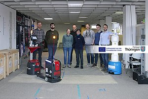 Das Projektteam aus acht Personen steht hinter drei autonomen Robotern. 