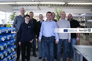 Seven men and one woman in a production room