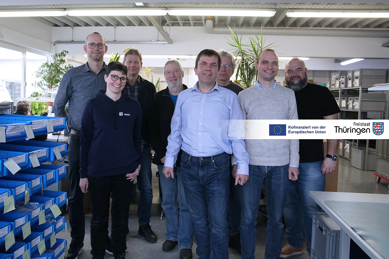 7 Männer und eine Frau in einem Fertigungsraum