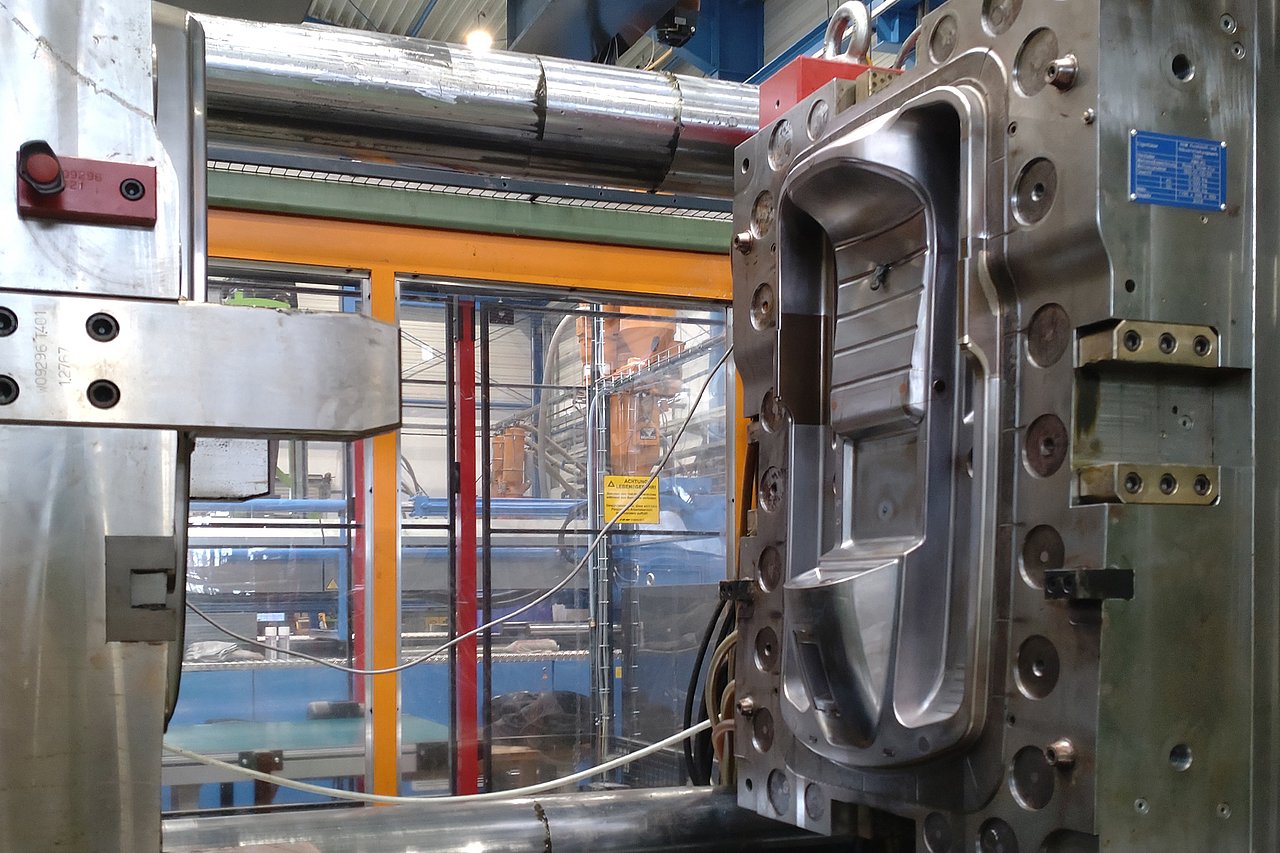 An dieser Spritzgussmaschine können dank KI mehr Schlitten produziert werden. Wie das geht, erfährt man zur Langen Nacht. Man kann Probesitzen, Rodelfotos machen und einen Schlitten gewinnen. Foto: IMMS. Eine geöffnete Spritzgussmaschine mit einer Gussform für Schlitten.